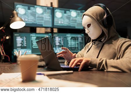 Hacker With Mask And Hood Breaking Security Server, Installing Virus To Create Computer Malware And 