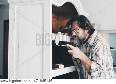 One Adult Man In Indoor Leisure Hobby Activity Painting An Old Wooden Cabinet Furniture Alone. Handy