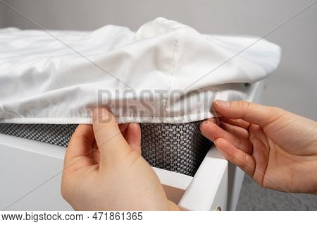 A White Satin Sheet With An Elastic Band Is Put On The Mattress Of The Bed, A Close-up Of The Hands.
