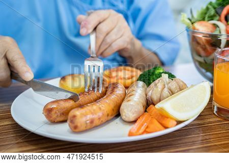 Asian Senio Woman Patient Eating Breakfast With Vegetable Healthy Food While Sitting And Hungry On B