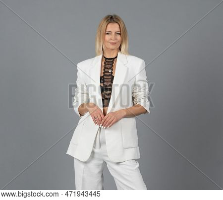 Portrait Of Blonde Woman With White Trousers Or Suit And Black Bralette, Underwear. Isolated On Gray
