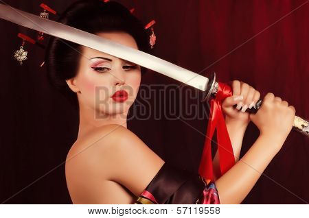 Beautiful geisha in kimono with samurai sword