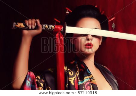 Beautiful geisha in kimono with samurai sword
