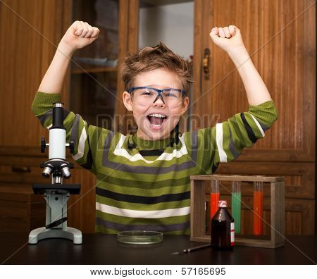 Happy boy with a microscope and colorful flasks