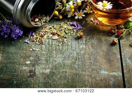 Herbal tea and wild organic flowers on wooden background
