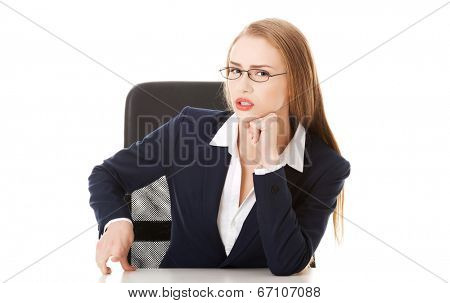 Attractive business woman by the table, bossy behaviour. Isolated on white.