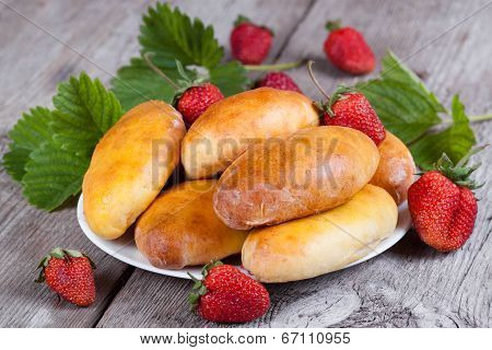 Fresh baked pasties with strawberries on plate close-up