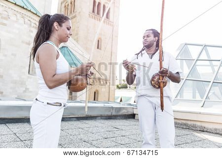 Young pair partners capoeira berimbau musical instrument in their hands