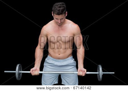 Serious crossfitter lifting up barbell on black background