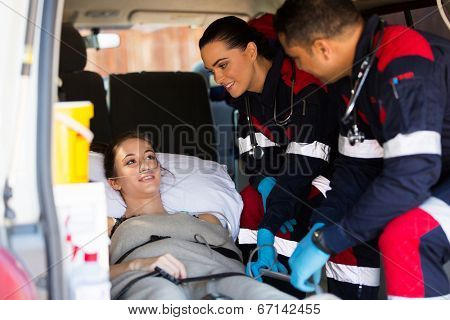 friendly paramedic team talking to patient in ambulance