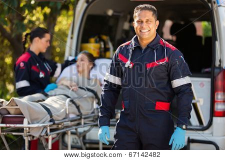 handsome paramedic with colleague and patient on background