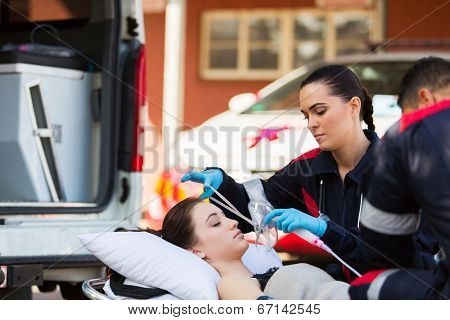 young female EMT putting oxygen mask on unconscious patient
