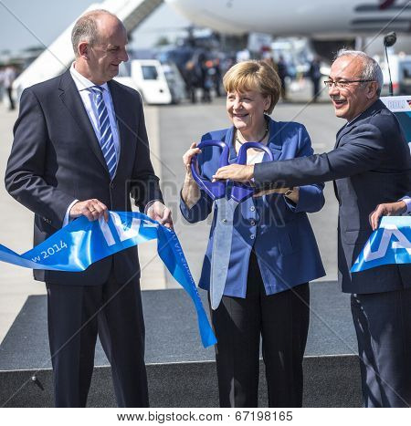BERLIN, GERMANY - MAY 20, 2014: German Chancellor Angela Merkel (C) and Turkish Minister of transport Lutfi Elvan (R) open up the International aviation and space exhibition ILA.