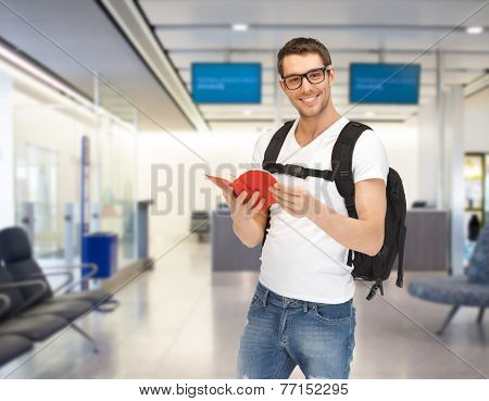 travel, education, tourism and people - smiling student with backpack and book at airport