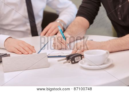 Close up of a male customer signing the contract