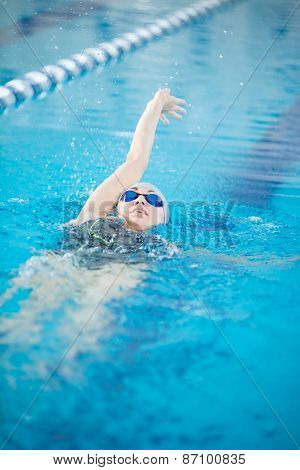 Young girl in goggles swimming back crawl stroke style