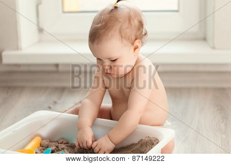 Little Girl Playing With Sand On Floor