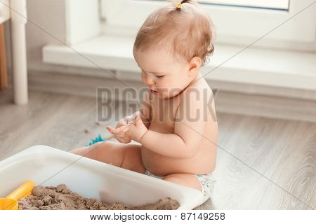 Little Girl Playing With Sand On Floor