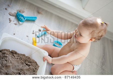 Little Girl Playing With Sand On Floor