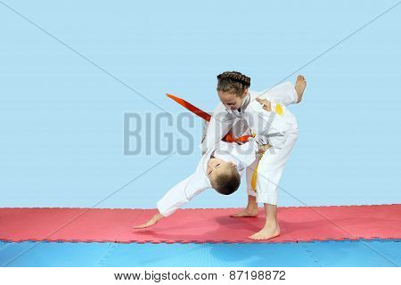Little girl rolls boy on the mats