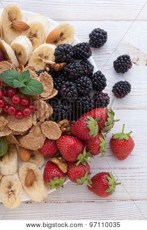 Breakfast - berries, fruit and muesli on white wooden