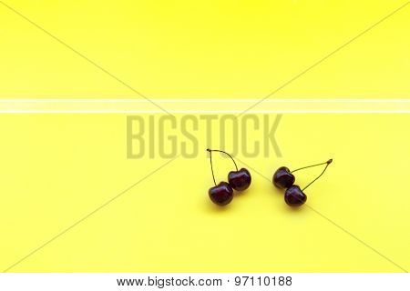 two couple sweet cherries on yellow background decotated with stripes