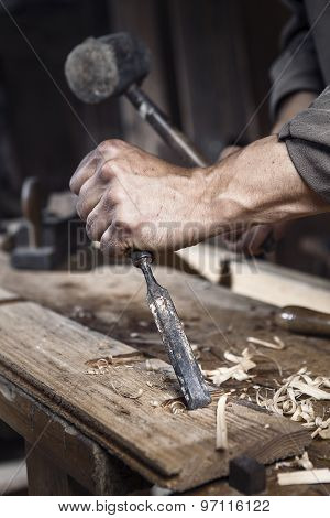 Hands Of Carpenter With A Hammer And Chisel