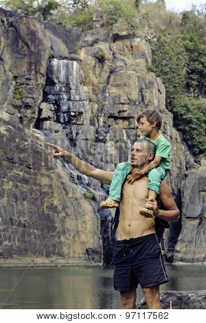 father and son making a trip to waterfall together, happy family on vacations, nature place