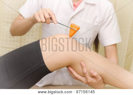 Female Doctor Doing Reflex Test On Patient's Knee