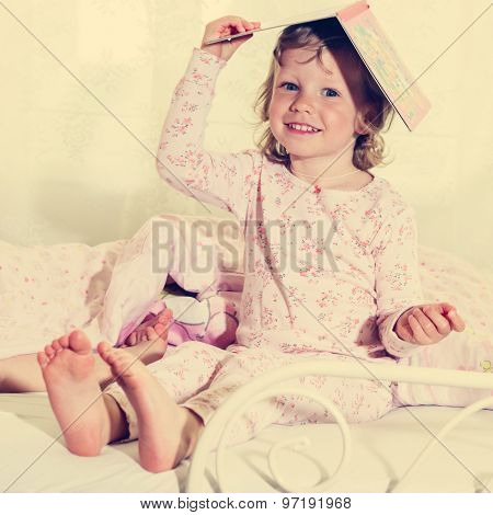 Beautiful Little Girl In The Crib With A Book On Your Head.