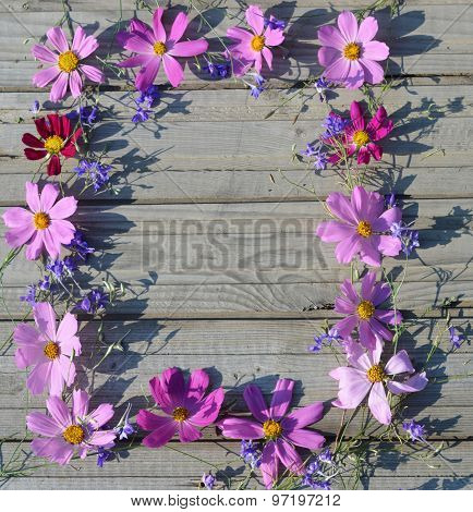 Frame of pink flowers on a background of boards