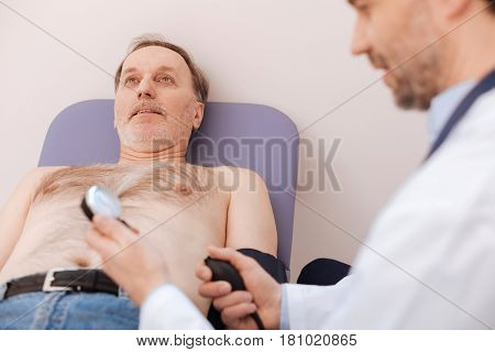 Just relax. Excellent competent young professional using a special blood pressure monitor while running a general checkup on mans health