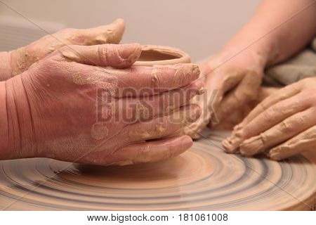 hands of a potter, creating an earthen jar on a pottery wheel
