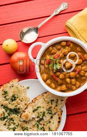 spicy chick peas curry or Chola Masala or Chana Masala or chole bhature or choley garnished with sliced onion and green coriander leaf, selective focus