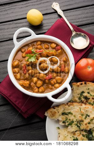 spicy chick peas curry or Chola Masala or Chana Masala or chole bhature or choley garnished with sliced onion and green coriander leaf, selective focus