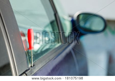 Anti theft system problem concept. Red screwdriver in car door after burglary