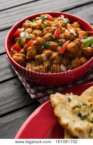 spicy chick peas curry or Chola Masala or Chana Masala or chole bhature or choley garnished with sliced onion and green coriander leaf, selective focus