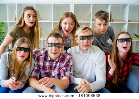 Friends in 3D glasses watching movie on sofa at home
