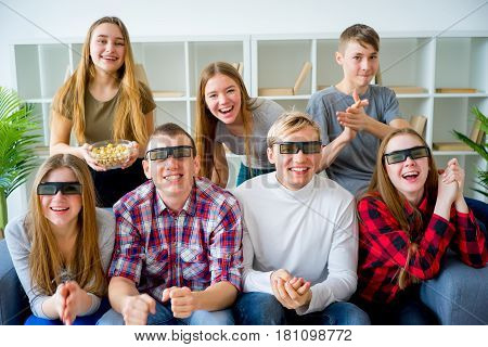 Friends in 3D glasses watching movie on sofa at home