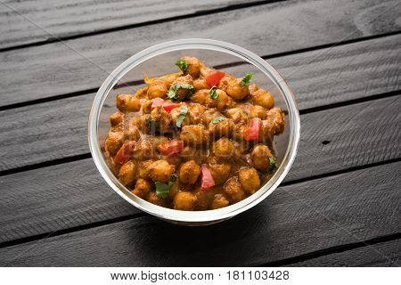 spicy chick peas curry or Chola Masala or Chana Masala or chole bhature or choley garnished with sliced onion and green coriander leaf, selective focus