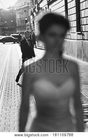 A Blurred Picture Of A Bride While Groom Folows Her Along The Street