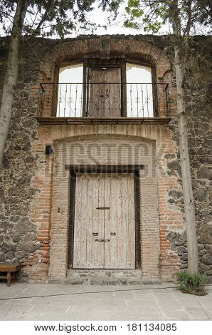VAL'QUIRICO, TLAXCALA, MEXICO-MARCH 25, 2017: Facade of a building with stone walls and an ancient door at a street in Val'Quirico, a new town near to Tlaxcala, Mexico