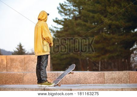 The boy is pondering standing with a skateboard