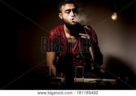 Young man with beard lost in the vices of alcoholism smoking and drug addiction