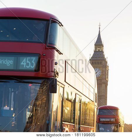 Traditionally red double-decker buses passing on Westminster Bridge in sunset in London, UK. Big ben and Palace of Westminster aka Houses of Parliament in background.