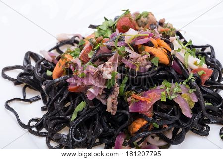Close up of black spaghetti with seafood and vegetables