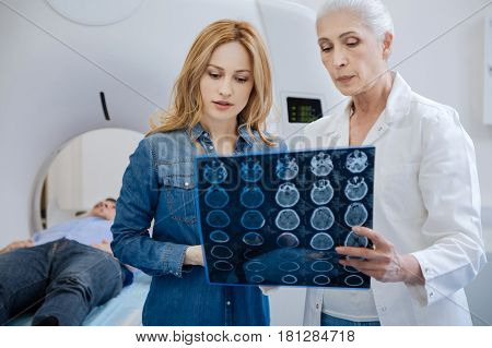 Worried about husband. Good looking nice pleasant woman looking at the X ray photo and listening to doctors explanations while being concerned about her husband