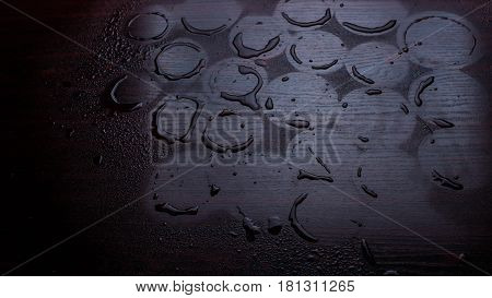 Empty wooden table with water drops against the background of autumn trees. The background is blurred. After the rain