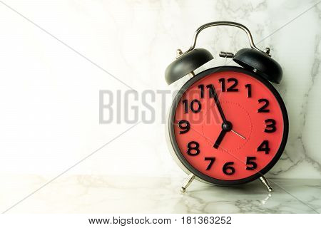 Red alarm clock on marble sureface counting at 7
