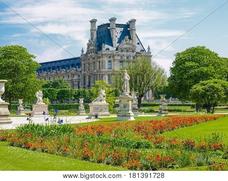 Corner of the Tuileries Garden with flower bed and alley with sculptures in Paris in springtime
